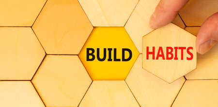 Build habits symbol. Concept word Build habits on beautiful wooden puzzles. Businessman's hand....