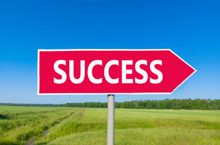 Success symbol. Concept word Success on beautiful red road sign. Beautiful blue sky green grass and...