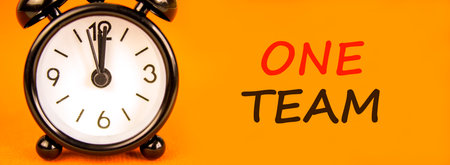 One team symbol. Concept word One team on beautiful orange paper. Beautiful black alarm clock....