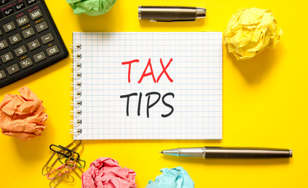 Tax tips symbol. Concept word Tax tips on beautiful white note. Black calculator. Black pen. Beautiful yellow paper background. Business tax tips concept. Copy space.の写真素材