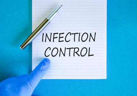 Infection control symbol. Concept words Infection control on beautiful white note. Doctor's hand in blue medical glove. Beautiful blue background. Medical healthy lifestyle infection control concept.の写真素材
