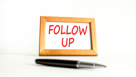 Follow up symbol. Concept word Follow up on beautiful wooden picture frame. Black pen. Beautiful white paper background. Business follow up concept. Copy space.の写真素材