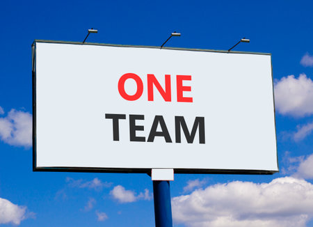 One team symbol. Concept word One team on beautiful white billboard. Beautiful blue sky and clouds background. Business one team concept. Copy space.の写真素材
