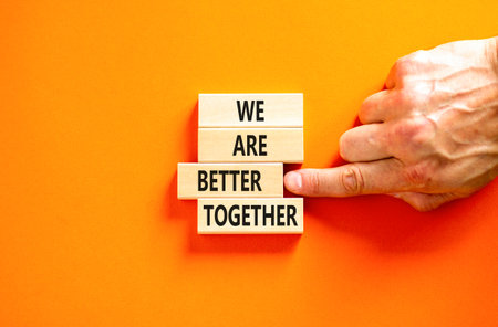 We are better together symbol. Concept words phrase We are better together on beautiful wooden blocks. Beautiful orange background. Businessman hand. Business We are better together concept Copy spaceの写真素材