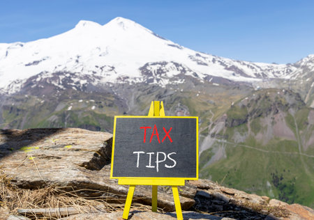 Tax tips symbol. Concept word Tax tips on beautiful black blackboard. Beautiful stone mountain...