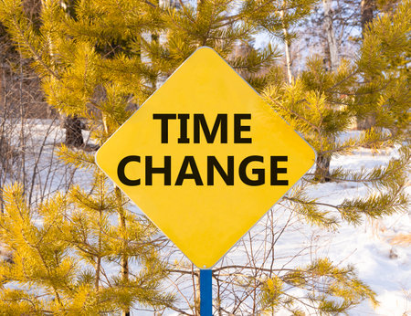 Time change symbol. Concept word Time change on beautiful yellow road sign. Beautiful snow winter forest background. Business time change concept. Copy space.の写真素材