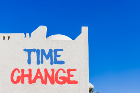 Time change symbol. Concept word Time change on beautiful white wall. Beautiful blue sky background. Business time change concept. Copy space.の写真素材