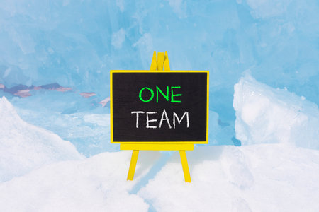 One team symbol. Concept word One team on beautiful black blackboard. Beautiful Baikal blue ice and snow background. Black blackboard. Business one team concept. Copy space.の写真素材