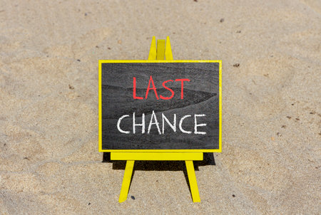 Last chance symbol. Concept word Last chance on beautiful black blackboard. Beautiful sand beach background. Black blackboard. Business last chance concept. Copy space.の写真素材