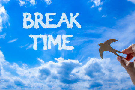 Break time symbol. Concept Break word time on beautiful blue sky. Businessman's hand with wooden bird. Beautiful blue sky and cloud background. Business break time concept. Copy space.の写真素材
