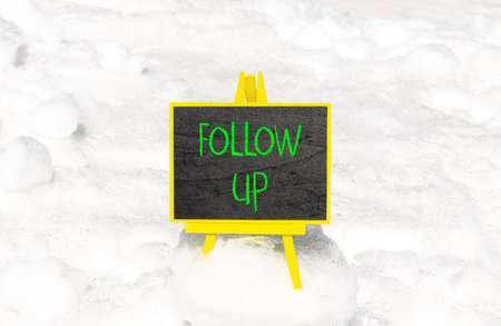 Follow up symbol. Concept word Follow up on beautiful black blackboard. Beautiful white snow background. White snow. Black blackboard. Business follow up concept. Copy space.の写真素材