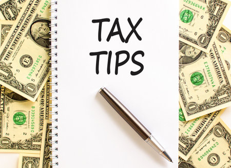 Tax tips symbol. Concept word Tax tips on beautiful white note. Dollar bills. Beautiful dollar bills background. Black pen. Business tax tips concept. Copy space.の写真素材