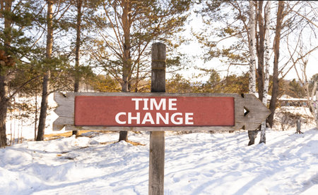Time change symbol. Concept word Time change on beautiful wooden road sign. Beautiful snow winter forest background. Business time change concept. Copy space.の写真素材