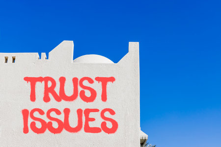 Trust issues symbol. Concept word Trust issues on beautiful white wall. Beautiful blue sky background. Business trust issues concept. Copy space.の写真素材