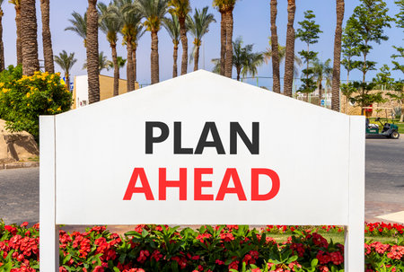 Plan ahead symbol. Concept word Plan ahead on beautiful white billboard. Beautiful blue sky and palm tree flowers background. Business plan ahead concept. Copy space.の写真素材