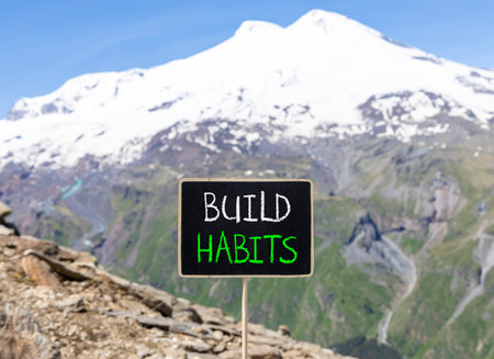 Build habits symbol. Concept word Build habits on beautiful black blackboard. Beautiful stone mountain Elbrus blue sky background. Black blackboard. Business build habits concept. Copy space.の写真素材