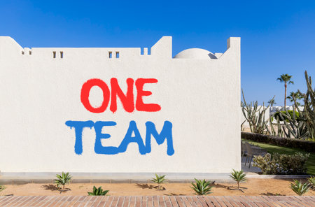 One team symbol. Concept word One team on beautiful white wall. Beautiful blue sky background. Business one team concept. Copy space.の写真素材