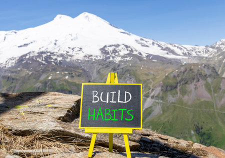 Build habits symbol. Concept word Build habits on beautiful black blackboard. Beautiful stone mountain Elbrus blue sky background. Black blackboard. Business build habits concept. Copy space.の写真素材