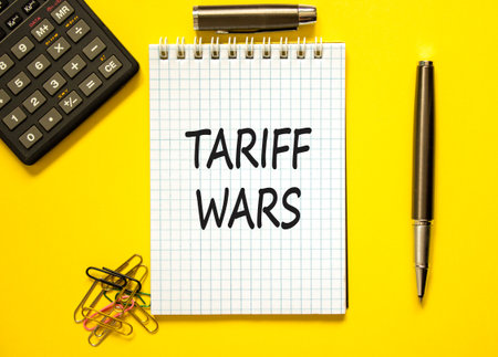 Trade tariff wars symbol. Concept word Tariff wars on beautiful white note. Black calculator. Black pen. Beautiful yellow paper background. Business trade tariff wars concept. Copy space.の写真素材