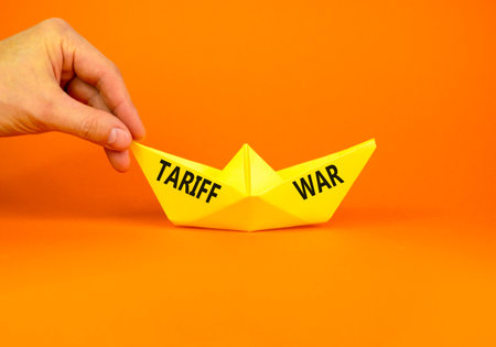 Trade tariff war symbol. Concept word Tariff war on beautiful yellow paper boat. Businessman's hand. Beautiful orange paper background. Business trade tariff wars concept. Copy space.の写真素材