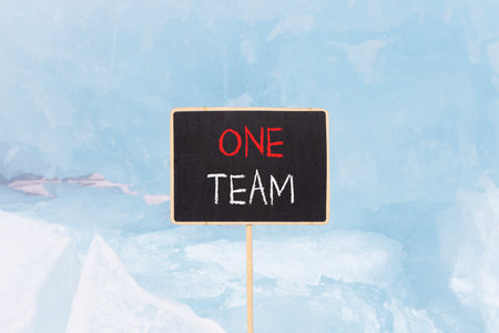 One team symbol. Concept word One team on beautiful black blackboard. Beautiful Baikal blue ice and snow background. Black blackboard. Business one team concept. Copy space.の写真素材