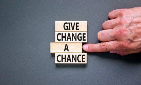 Give change a chance symbol. Concept words phrase Give change a chance on beautiful wooden blocks. Beautiful gray paper background. Businessman's hand. Business Give change a chance concept Copy spaceの写真素材