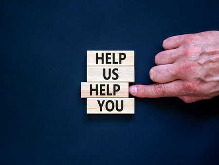 Help you symbol. Concept words phrase Help us help you on beautiful wooden blocks. Beautiful black paper background. Businessman's hand. Business Help you concept. Copy space.の写真素材