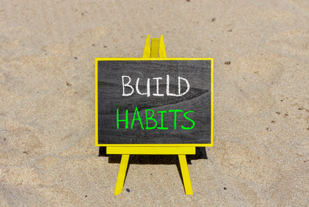 Build habits symbol. Concept word Build habits on beautiful black blackboard. Beautiful sand beach background. Black blackboard. Business build habits concept. Copy space.の写真素材
