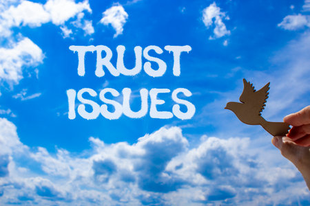 Trust issues symbol. Concept word Trust issues on beautiful blue sky. Businessman's hand with wooden...
