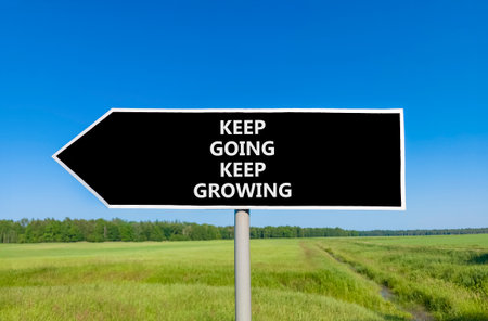 Keep going and growing symbol. Concept words phrase Keep going keep growing on beautiful road sign. Beautiful blue sky green grass lawn background. Business Keep going and growing concept. Copy space.の写真素材