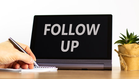 Follow up symbol. Concept word Follow up on beautiful black tablet. Businessman's hand with pen. Calculator. Beautiful white background. Business follow up concept. Copy space.の写真素材