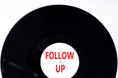 Follow up symbol. Concept word Follow up on beautiful black and white vinyl disk. Beautiful white paper background. Business follow up concept. Copy space.の写真素材