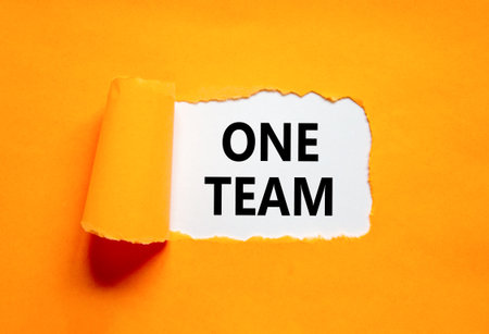 One team symbol. Concept word One team on beautiful white paper. Beautiful orange paper background. Business one team concept. Copy space.の写真素材