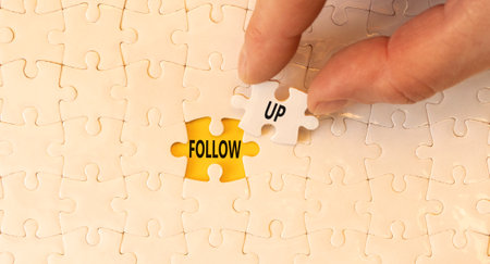 Follow up symbol. Concept word Follow up on beautiful white puzzles. Businessman's hand. Beautiful yellow paper background. Business follow up concept. Copy space.の写真素材