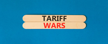 Trade tariff wars symbol. Concept word Tariff wars on beautiful wooden sticks. Beautiful blue paper background. Business trade tariff wars concept. Copy space.の写真素材