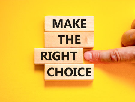 Make the right choice symbol. Concept words phrase Make the right choice on beautiful wooden blocks. Beautiful yellow background. Businessman's hand. Business Make the right choice concept. Copy spaceの写真素材