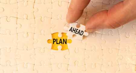 Plan ahead symbol. Concept word Plan ahead on beautiful white puzzles. Businessman's hand. Beautiful yellow paper background. Business plan ahead concept. Copy space.の写真素材