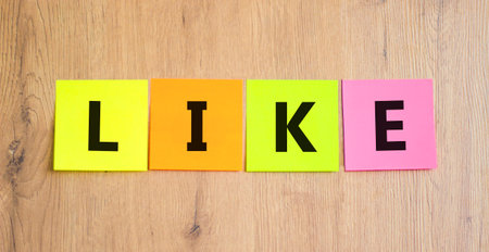 Like symbol. Concept word Like on beautiful colored paper. Beautiful wooden table wooden background....
