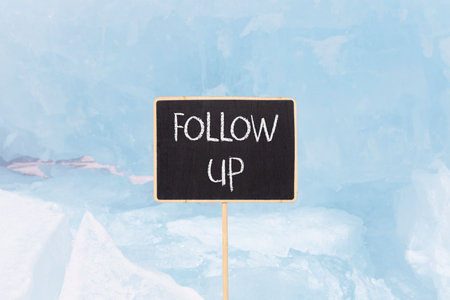 Follow up symbol. Concept word Follow up on beautiful black blackboard. Beautiful blue Baikal ice...