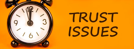 Trust issues symbol. Concept word Trust issues on beautiful orange paper. Beautiful black alarm...