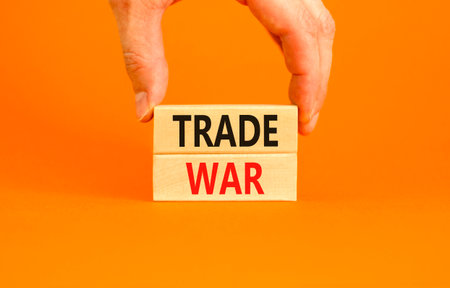 Trade war symbol. Concept word Trade war on beautiful wooden blocks. Beautiful orange paper background. Businessman's hand. Business trade war concept. Copy space.の写真素材