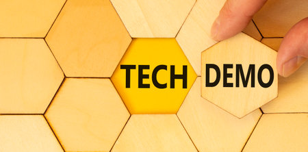 Tech demo symbol. Concept word Tech demo on beautiful wooden puzzles. Businessman's hand. Beautiful yellow paper background. Business tech demo concept. Copy space.の写真素材