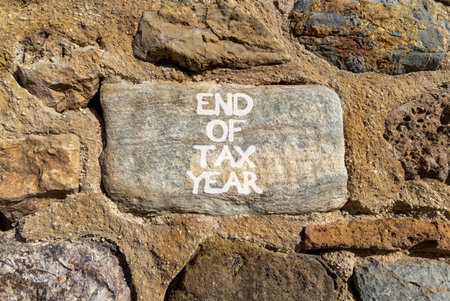 End of tax year symbol. Concept words phrase End of tax year on beautiful gray stone wall. Beautiful...