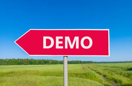 Demo symbol. Concept word Demo on beautiful red road sign. Beautiful blue sky green grass and forest...