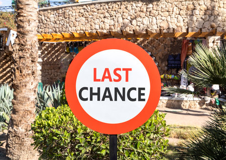 Last chance symbol. Concept word Last chance on beautiful red and white road sign. Beautiful palm...
