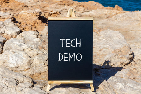 Tech demo symbol. Concept word Tech demo on beautiful black blackboard. Beautiful stone and blue sea...