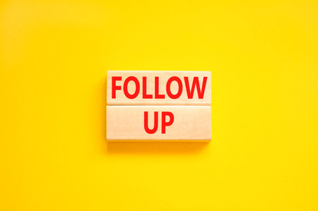 Follow up symbol. Concept word Follow up on beautiful wooden blocks. Beautiful yellow paper background. Business follow up concept. Copy space.の写真素材
