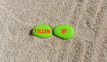 Follow up symbol. Concept word Follow up on beautiful green stones. Sea sand beach. Beautiful sand beach background. Business follow up concept. Copy space.の写真素材