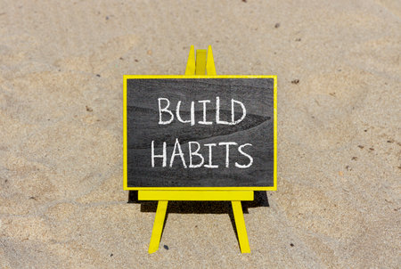 Build habits symbol. Concept word Build habits on beautiful black blackboard. Beautiful sand beach...