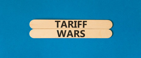 Trade tariff wars symbol. Concept word Tariff wars on beautiful wooden sticks. Beautiful blue paper background. Business trade tariff wars concept. Copy space.の写真素材